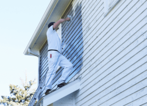 man doing exterior painting of house